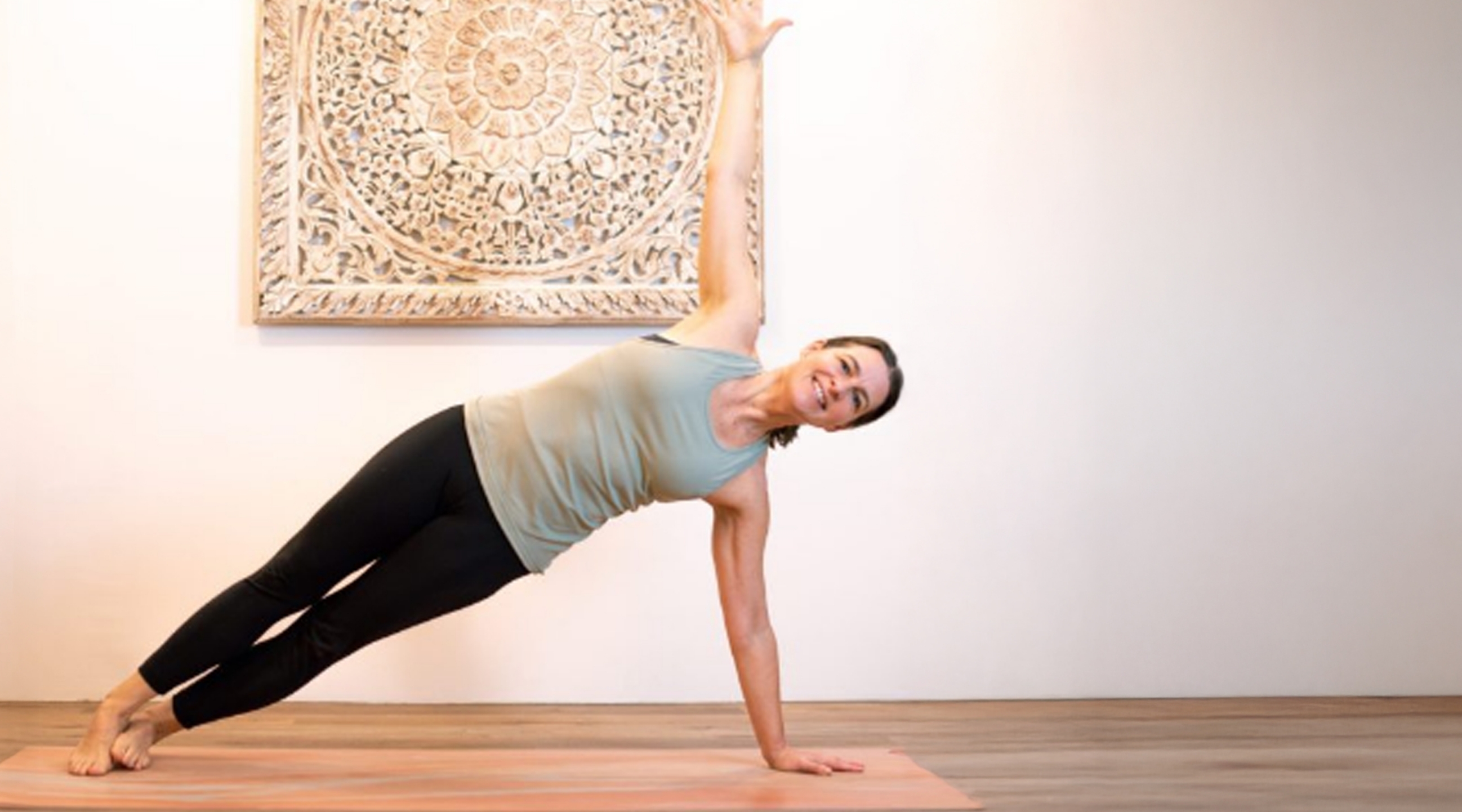Heike Cabrera in einer Side-Plank-Pose in einem hellen Raum.