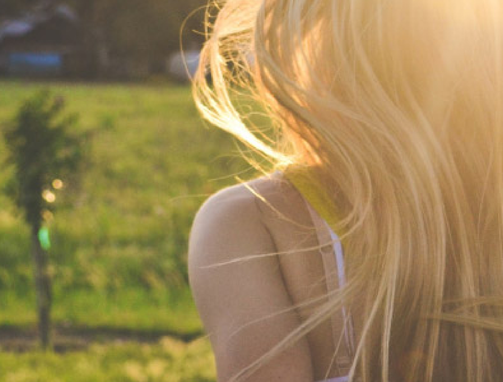 Blonde Person im warmen Sonnenlicht auf einer Wiese.